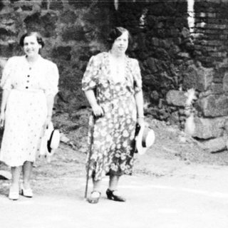 People stand near an arched stone structure.