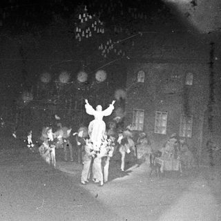 People gather around a figure with arms raised.