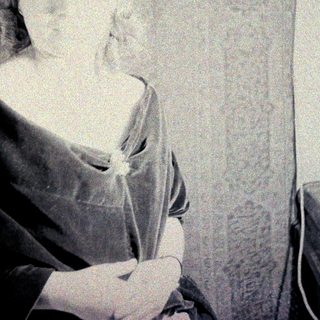 Here's a brief summary of the image: Portrait of a woman in historical dress, seated indoors.