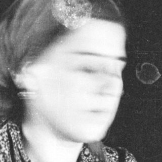 Black and white portrait of a woman in a patterned dress.