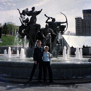 Couple poses near a fountain with a statue.