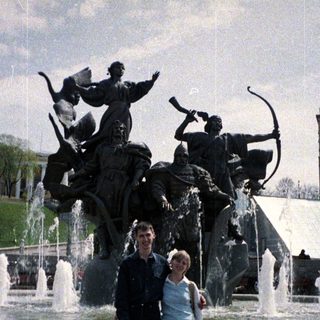 Couple poses near a fountain with a statue.
