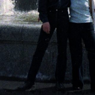 Couple poses near a fountain with a statue.