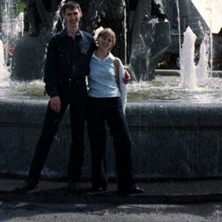Couple poses near a fountain with a statue.