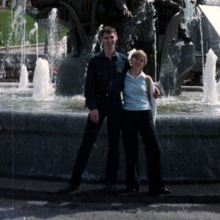 Couple poses near a fountain with a statue.