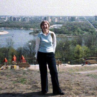Woman stands overlooking a cityscape and river landscape.