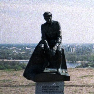 Woman poses near statue overlooking a city and river.