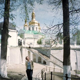 Woman walks towards a church with golden domes.
