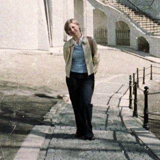 Woman walks towards a church with golden domes.