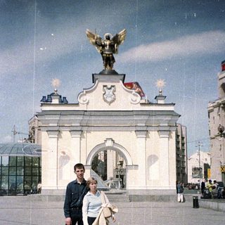 Couple poses in front of an ornate monument.