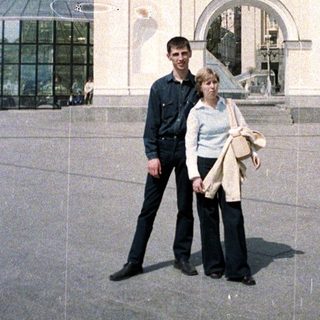 Couple poses in front of an ornate monument.