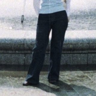 Woman stands near a fountain in a public park.