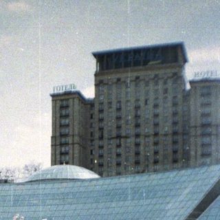 People stroll through a fountain plaza with architectural structures.