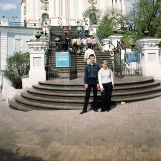 Two people stand before a large, ornate church building.