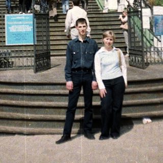 Two people stand before a large, ornate church building.
