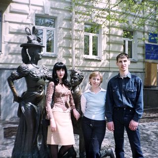 People posing near a statue in front of a building.