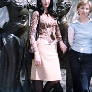 People posing near a statue in front of a building.