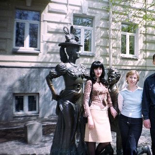 People posing near a statue in front of a building.