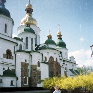 Woman stands before a large, ornate, domed church building.