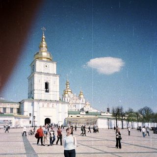 Woman stands before a large, ornate church complex.