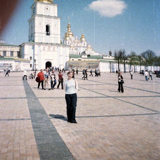 Woman stands before a large, ornate church complex.