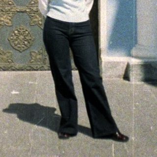 Woman stands before an ornate doorway and facade.