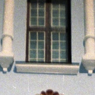 Woman stands before an ornate doorway and facade.