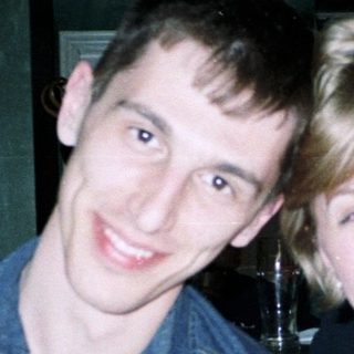 Two people smiling at a bar, food visible.