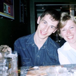 Two people smiling at a bar, food visible.