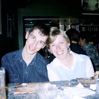 Two people smiling at a bar, food visible.