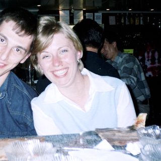Two people smiling at a bar, food visible.