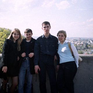 Four people stand on a ledge overlooking a cityscape.
