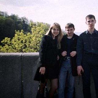Four people stand on a ledge overlooking a cityscape.