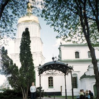 Woman stands near a building and ornate structure.