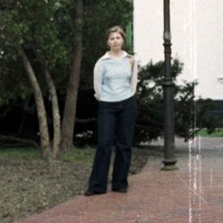Woman stands near a building and ornate structure.