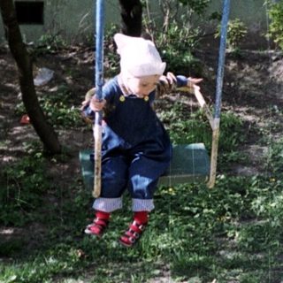 Child swings playfully on a swing set outdoors.