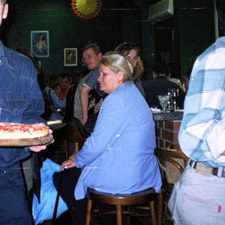 Man holds pizza in a bowling alley setting.