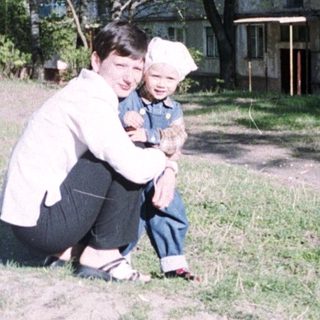 Person and child in a park near an apartment building.