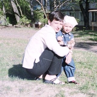Person and child in a park near an apartment building.