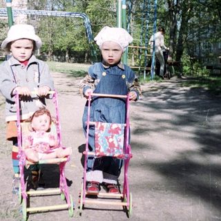 Two young children play with dolls on a playground.