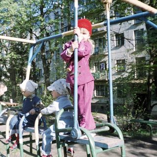 Children play on a playground structure in a park.