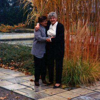 Two women stand in a garden with tall ornamental grass.
