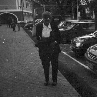Person walking past parked cars on a dark street.