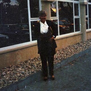 Man stands outside building with arched windows and landscaping.