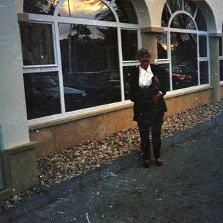 Man stands outside a building with arched windows.