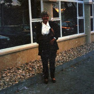Man stands outside a building with arched windows.