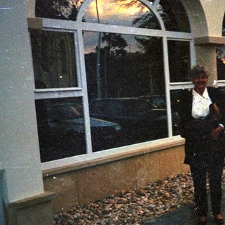 Man stands outside a building with arched windows.