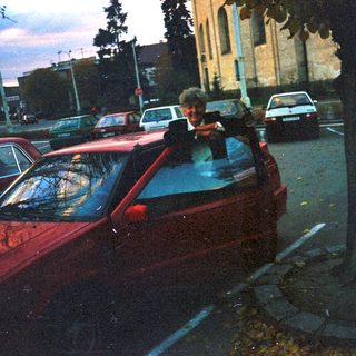 Man stands near parked cars on a street.