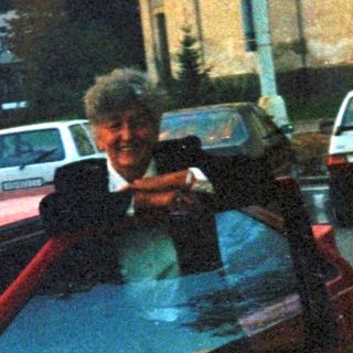 Man stands near parked cars on a street.