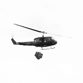 Helicopter in flight, carrying a suspended load.